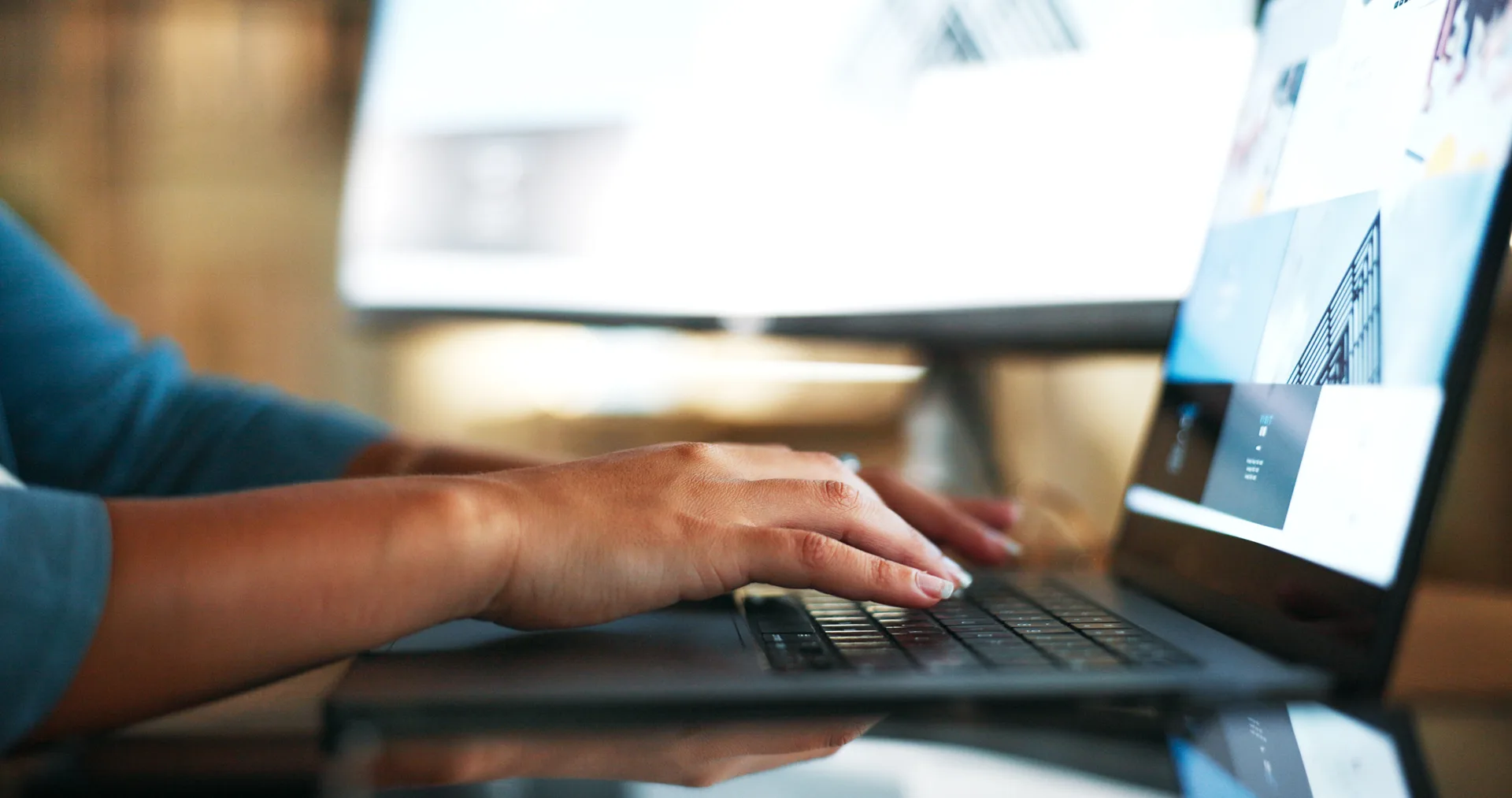 Hands typing on a laptop in an office